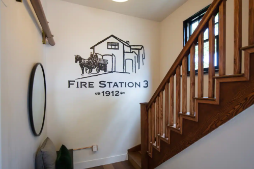 Interior of a home featuring a staircase and a wall mural of Fire Station 3, established in 1912, with a horse-drawn fire truck.